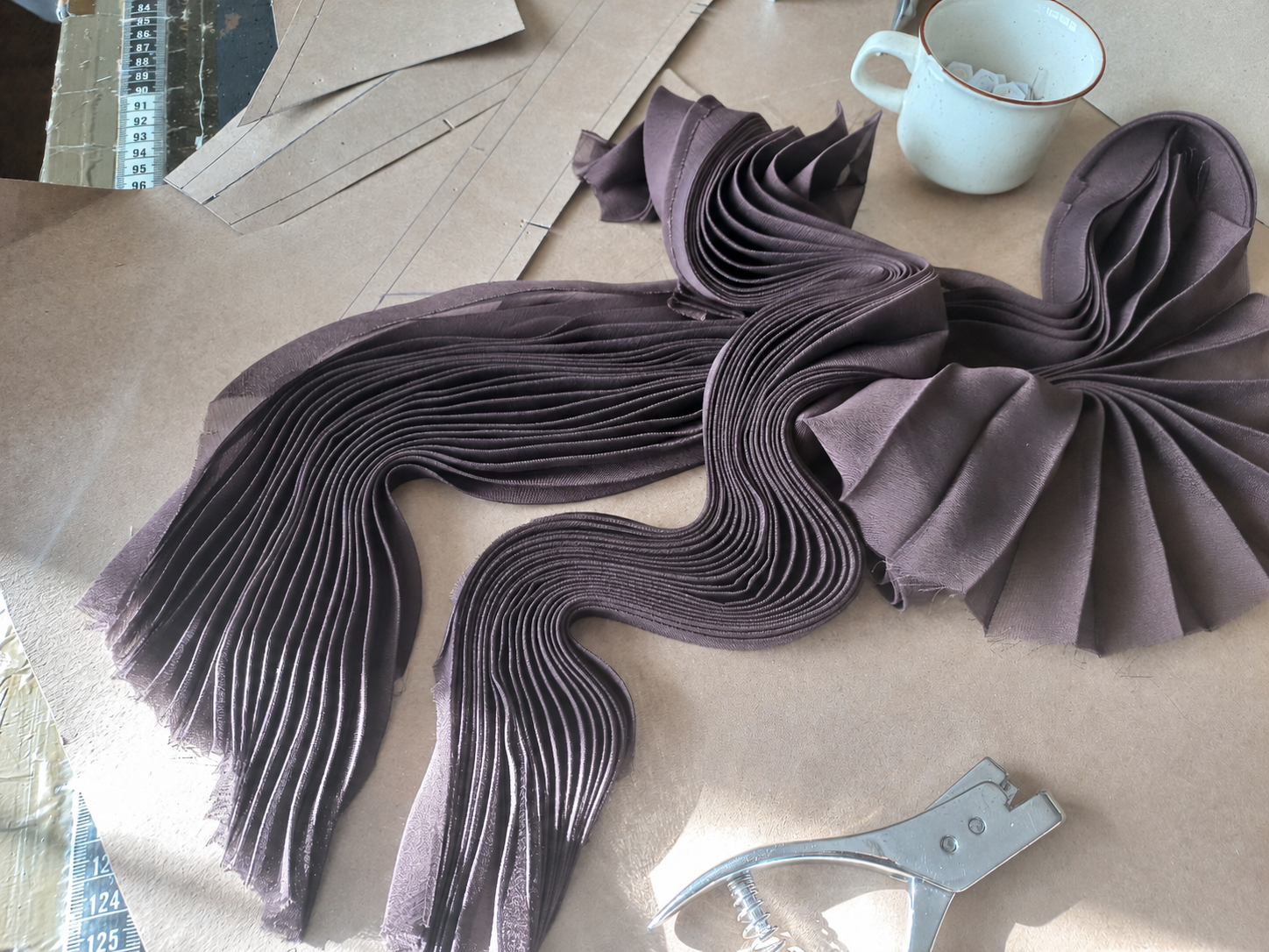 Dusty plum pleated garment components being tested during sample development